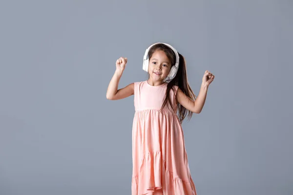 Маленька дівчинка в сукні і навушники слухає музику і танці — стокове фото