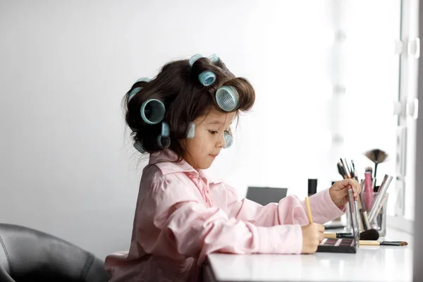 Schattig klein meisje speelt met haar moeders cosmetische — Stockfoto