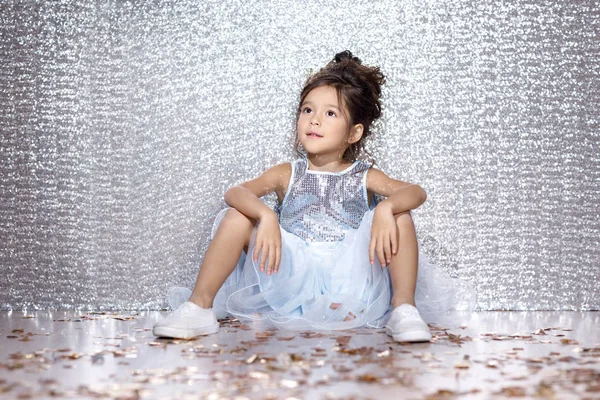 Little child girl in dress sitting on the floor with confetti — Stock Photo, Image
