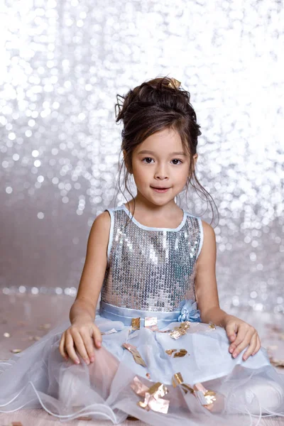 Gadis kecil bergaun biru duduk di lantai dengan confetti — Stok Foto