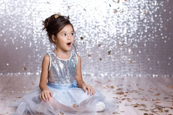 Gadis kecil bergaun biru duduk di lantai dengan confetti — Stok Foto