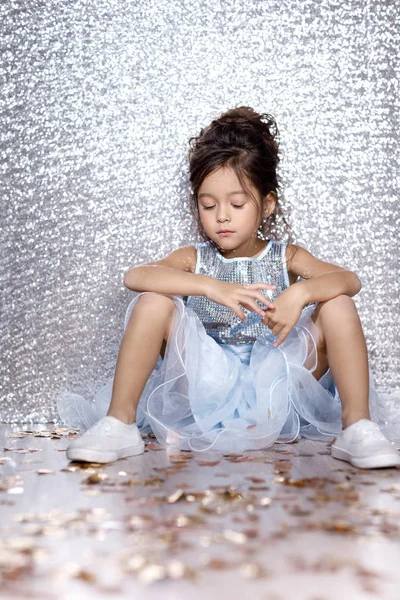 Little child girl in dress sitting on the floor with confetti — Stock Photo, Image