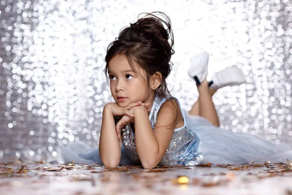 Little girl in blue dress sitting on the floor with confetti — Stock Photo, Image