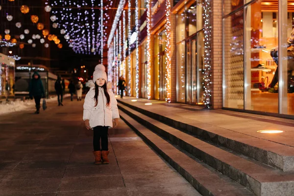 Cute scared lost little girl in a big city in the evening in winter
