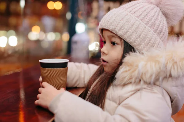 Linda niña feliz bebe té caliente en un café de la calle — Foto de Stock