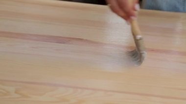 Kadın elinde fırça ahşap masa vernikler.