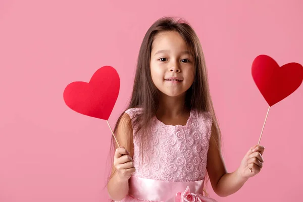 Schattig klein meisje in een roze jurk houden een papier-hart — Stockfoto