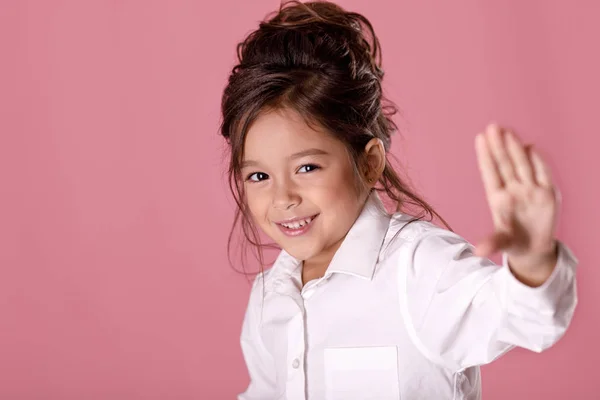 Φοβισμένη χαριτωμένο μικρό κορίτσι σε λευκό πουκάμισο κάνοντας στάση χειρονομία σε ροζ φόντο. Ανθρώπινα συναισθήματα και τις εκφράσεις του προσώπου — Φωτογραφία Αρχείου