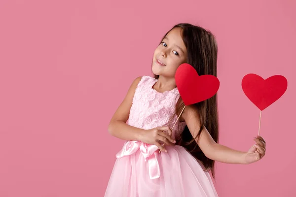 Schattig klein meisje in een roze jurk houden een papier-hart — Stockfoto