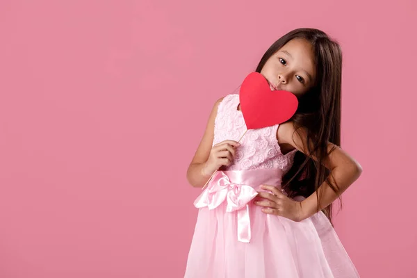 Mignonne petite fille dans une robe rose tenant un coeur en papier — Photo