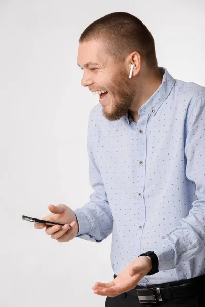 Vousatý podnikatel využívá bezdrátové sluchátka a smartphone — Stock fotografie
