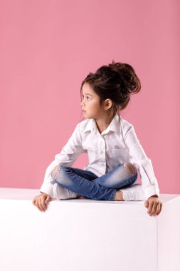 lotus bulunduğu sakin küçük çocuk kız saç modeli ile beyaz gömlekli oturur