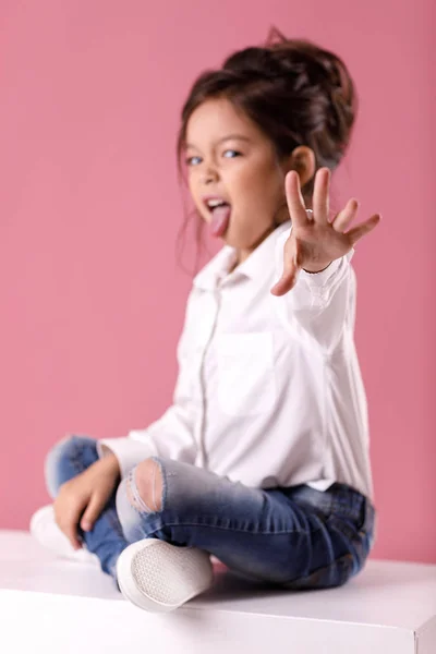 Linda niña en camisa blanca con peinado mostrando la lengua — Foto de Stock