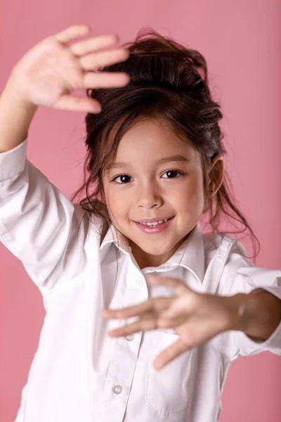 Niedliches verängstigtes kleines Mädchen in weißem Hemd macht Stop-Geste auf rosa Hintergrund. menschliche Emotionen und Mimik — Stockfoto