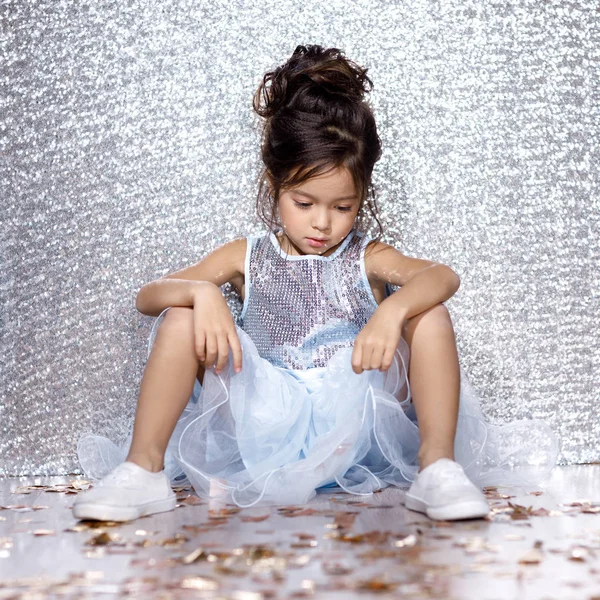 Pieni lapsi tyttö mekko istuu lattialla konfetti — kuvapankkivalokuva