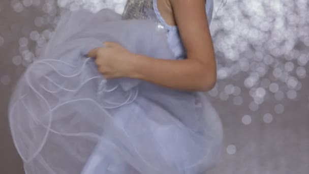 Little girl child in a silver dress dancing on background of silver bokeh. — Stock Video