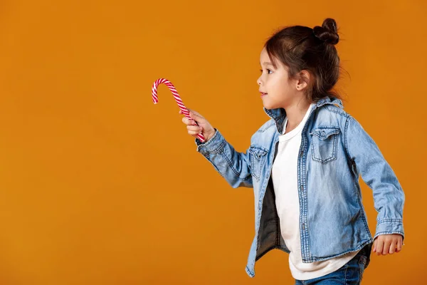 Menina feliz em jeans roupas segurando pirulito — Fotografia de Stock