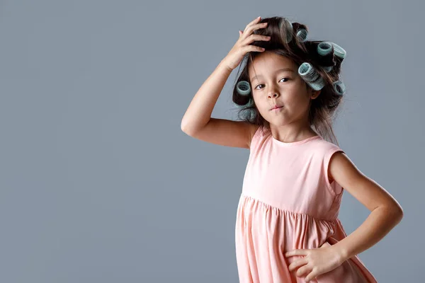 Cute little child girl in pink dress and hair curlers — Stock Photo, Image