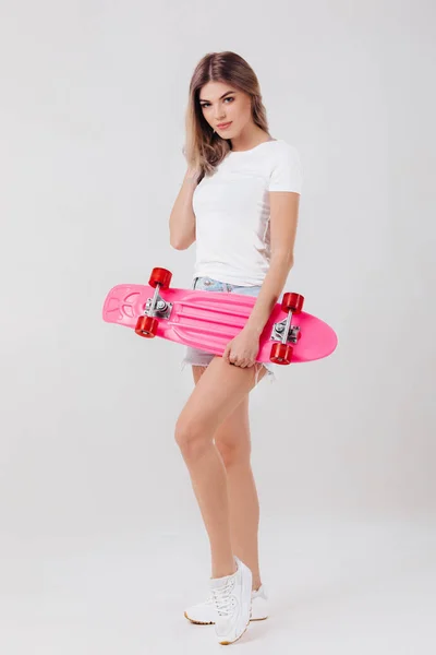 Mooie vrouw in wit t-shirt met roze skateboard — Stockfoto