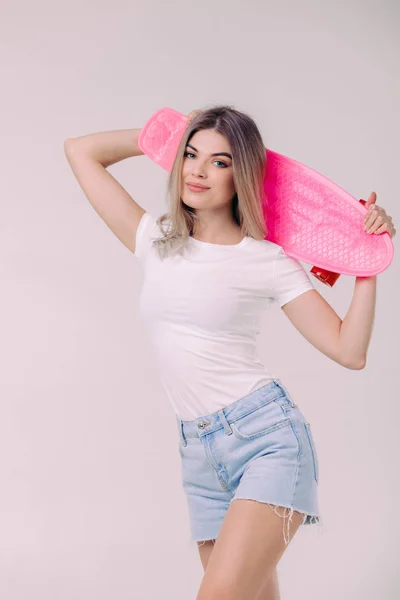 Bela mulher em t-shirt branca com skate rosa — Fotografia de Stock