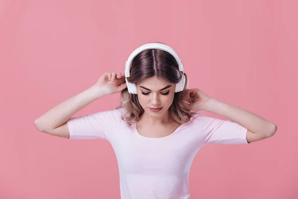 Bela mulher loira em fones de ouvido brancos escuta música — Fotografia de Stock