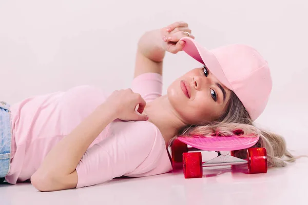 Vacker kvinna i vit t-shirt med rosa skateboard — Stockfoto