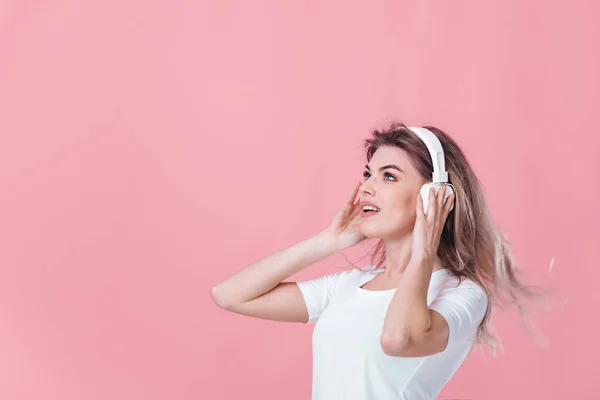 Hermosa mujer rubia en auriculares blancos escucha música — Foto de Stock