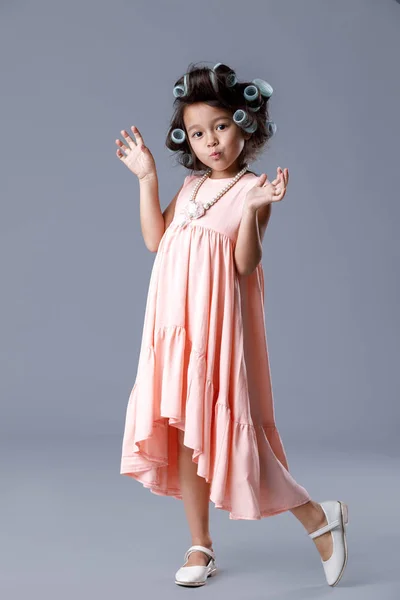 Menina bonito pequeno em vestido rosa e encrespadores de cabelo — Fotografia de Stock