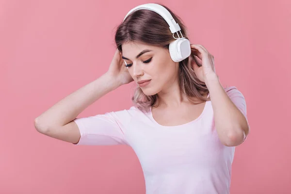 Bela mulher loira em fones de ouvido brancos escuta música — Fotografia de Stock