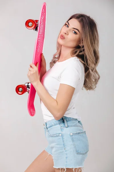 Красивая женщина в белой футболке с розовым скейтбордом — стоковое фото