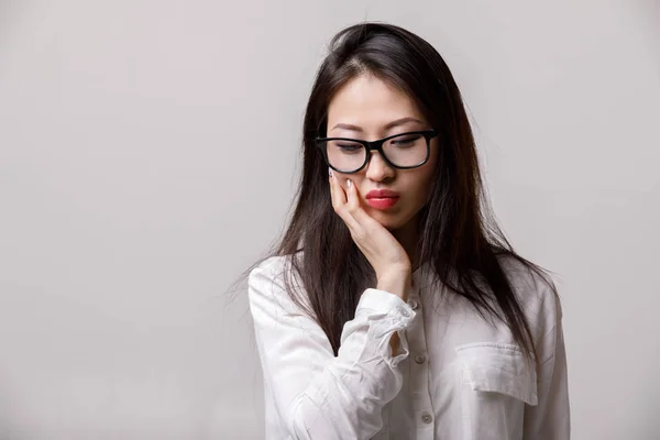 Ritratto di donna asiatica triste in occhiali e camicia bianca — Foto Stock