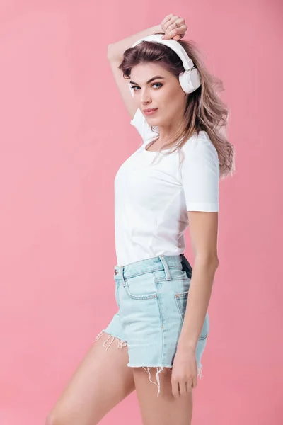 Hermosa mujer rubia en auriculares blancos escucha música — Foto de Stock