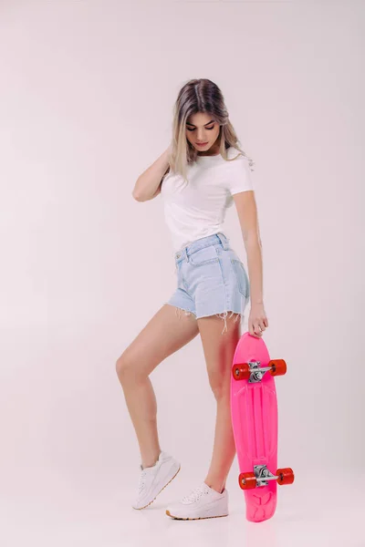 Bela mulher em t-shirt branca com skate rosa — Fotografia de Stock