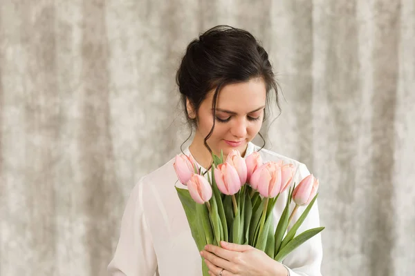 Beautiful brunette woman with a bouquet of tulips flowers — Stock Photo, Image