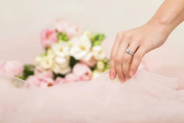 Mão de noivas com uma aliança de casamento no fundo das flores — Fotografia de Stock