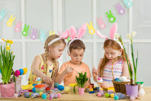 милые дети рисуют пасхальные яйца дома
.