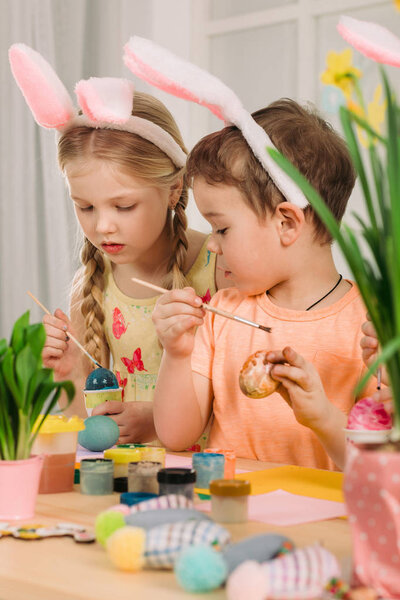 милые дети рисуют пасхальные яйца дома
.