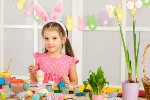 Bambina bambina con le orecchie di coniglio di Pasqua pittura uova di Pasqua a casa . — Foto Stock