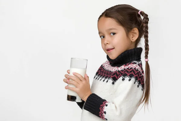 Lilla barn flicka håller glas mjölk på vit bakgrund — Stockfoto