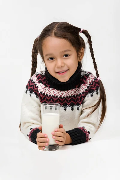 Маленька дівчинка тримає склянку молока на білому тлі — стокове фото