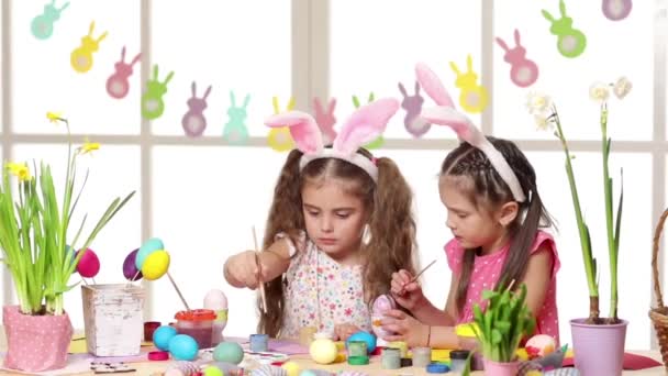 Bambini felici che indossano orecchie di coniglio che dipingono uova il giorno di Pasqua . — Video Stock
