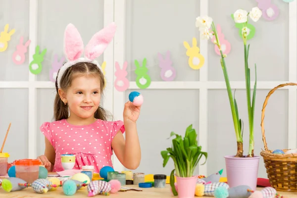 Bambina bambina con le orecchie di coniglio di Pasqua pittura uova di Pasqua a casa . — Foto Stock