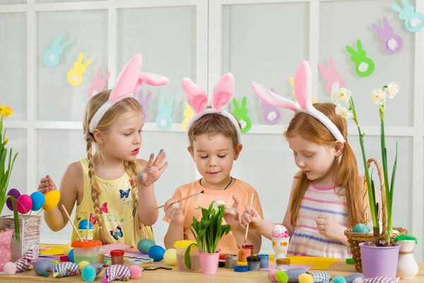 милые дети рисуют пасхальные яйца дома
.