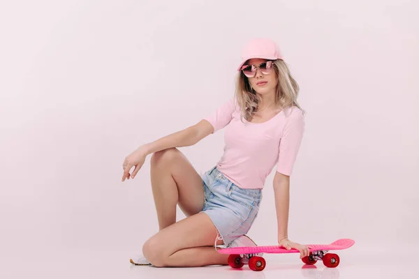 Vacker kvinna i vit t-shirt med rosa skateboard — Stockfoto