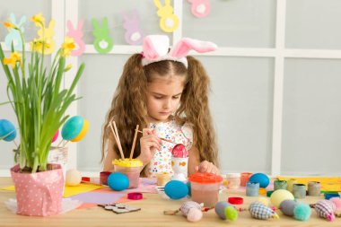 Paskalya yumurtaları evde boyama Paskalya tavşan kulaklı kız küçük çocuk.