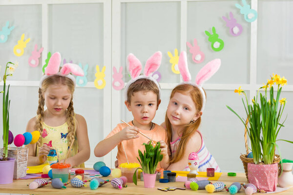 милые дети рисуют пасхальные яйца дома
.