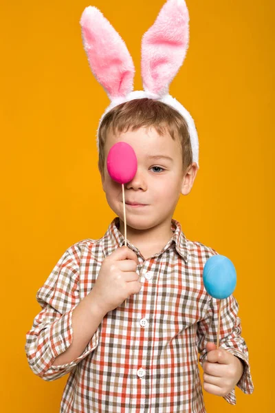 Menino com orelhas de coelho de Páscoa segurando ovos coloridos — Fotografia de Stock