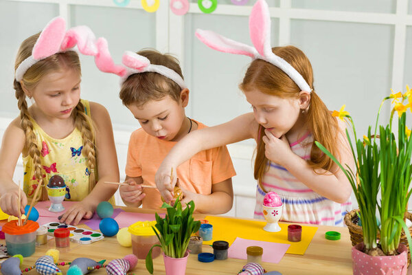 милые дети рисуют пасхальные яйца дома
.