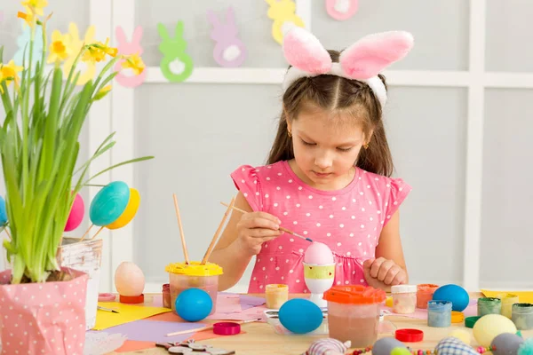 Małe dziecko dziewczyna z Easter bunny uszy pisanki w domu. — Zdjęcie stockowe
