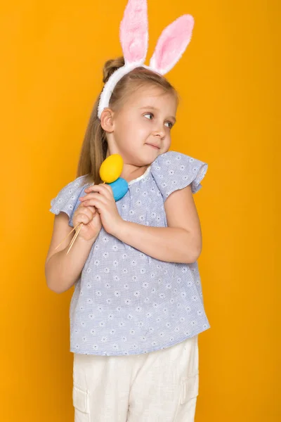 Cute little girl with Easter bunny ears holding colorful eggs — Stock Photo, Image